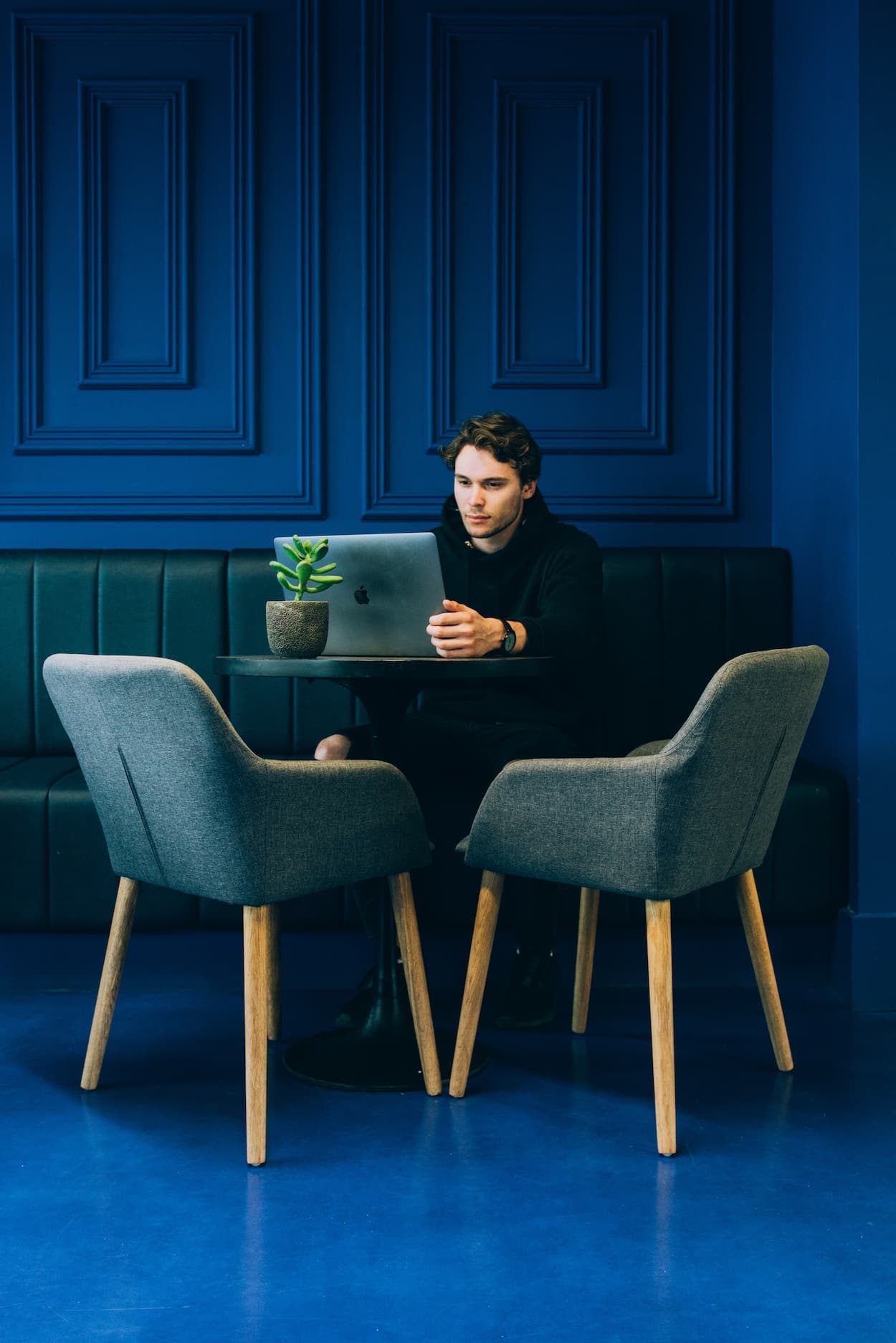 A person working on a laptop in a blue room.